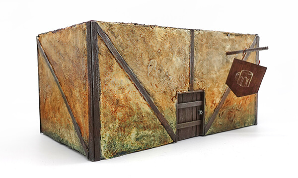 tabletop tavern terrain piece showing the front of the building, wooden door and broken sign hanging from the front with a beer mug drawn on it
